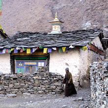 Foto eines Hauses an der Grenze zum Himalaya. Am Dach hängen tibetische Gebetsfahnen. 