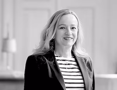 Frauenporträt in Schwarzweiß. Eine ältere Frau lächelt den Betrachter an. Sie trägt schulterlanges Haar.