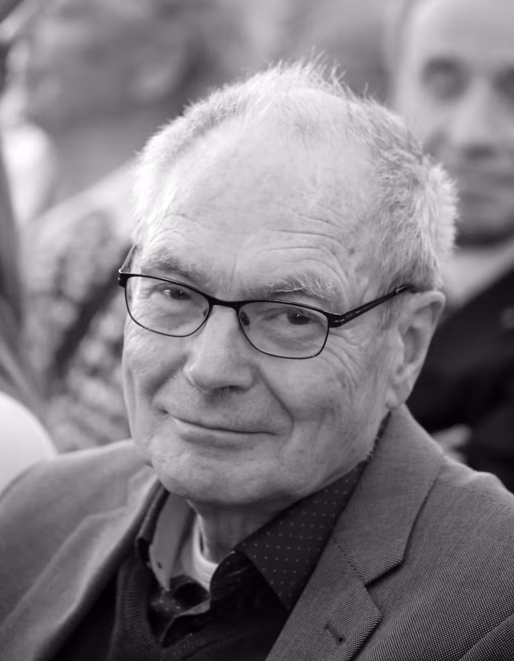 Schwarz-weiß-Porträt eines älteren Mannes mit Brille (Hilbert von Löhneysen), der den Betrachter anlächelt.