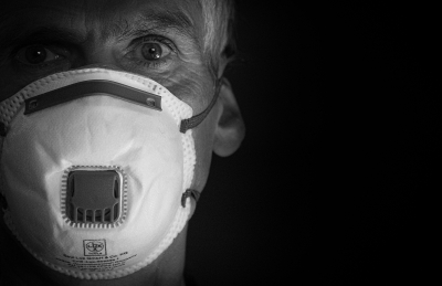  Nahaufnahme von einem älteren Mann, der eine FFP3 Maske trägt und in die Kamera schaut.