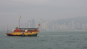 Im Hintergrund Hongkong im Smog, im Vordergrund ein gelbrotes Fischerboot