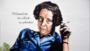 Graffito: BeneR1 und koart an Arendts GeburtshausHannah Arendt, Arendt sitzt in blauer Bluse und mit Zigarette in der Hand da und schaut die Betrachtenden an, neben ihrem Kopf steht "Niemand hat das Recht zu gehorchen"
