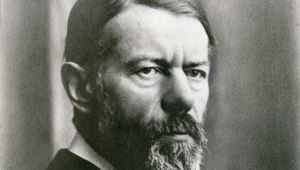 Schwarzweißfoto von Max Weber, der im Dreiviertelprofil zu sehen ist. Er blickt ernst zur rechten Seite (vom Betrachter aus gesehen). Er trägt einen Vollbart und die Haare sind zum Seitenscheitel gekämmt.