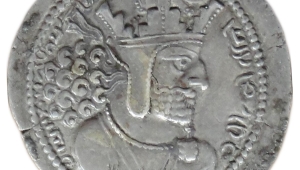 Silbermünze mit Prägung des Profils des Königs Schapur I., er ist mit einem dichten Bart, langem, gelockten Haar und strengem Blick dargestellt. Auf dem Kopf trägt er eine Krone