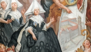 Ausschnitt des Freskos mit einer figürlichen Szene. Die zeitgenössische Erneuerung des Stifts wird vor allem durch die Auftraggeberin der Kirchenausstattung dargestellt: Äbtissin Maria Maximiliana Esther von Stadion zu Tannhausen und Warthausen. Sie deutet auf einen Plan des neugebauten Konventsgebäudes. Sie ist umgeben von Engeln und hinter ihr stehen weitere Nonnen. 