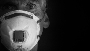  Nahaufnahme von einem älteren Mann, der eine FFP3 Maske trägt und in die Kamera schaut.