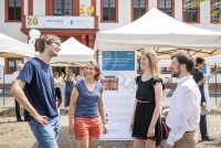Eine Gruppe von Personen unterhält sich bei den Informationsständen zu den Projekten des Wissenschaftlichen Nachwuchses der Heidelberger Akademie.