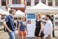 Eine Gruppe von Personen unterhält sich bei den Informationsständen zu den Projekten des Wissenschaftlichen Nachwuchses der Heidelberger Akademie.